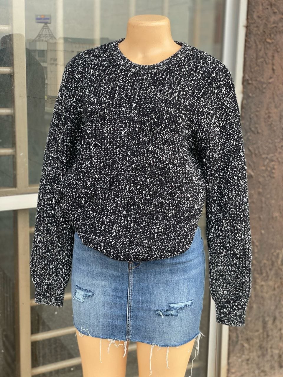 black and white speckled sweater with a denim mini skirt